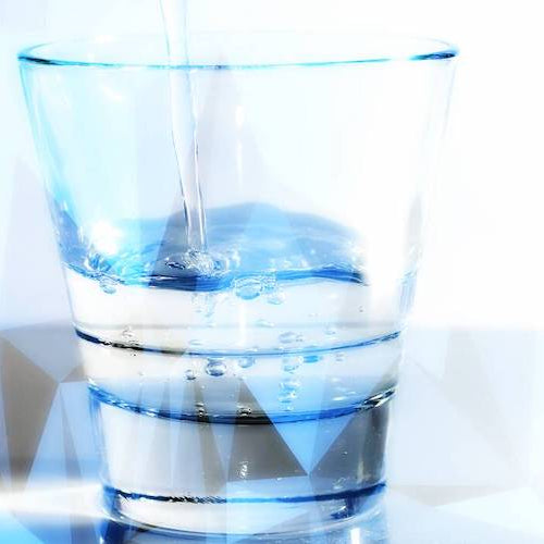 Glas water naast een leeg wijnglas om uitdroging door alcohol te illustreren